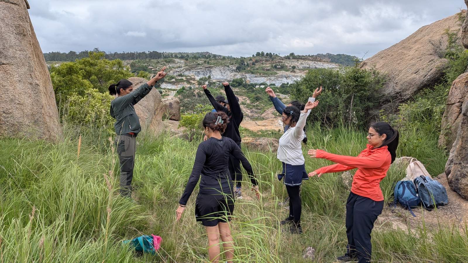 A group of adults stretching together on a hilltop