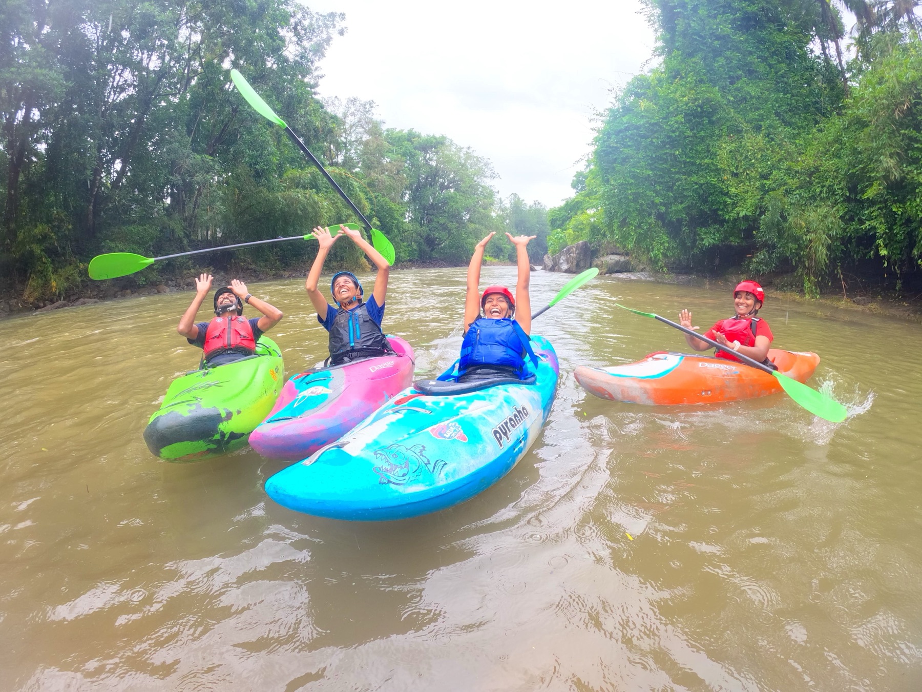 Kayakers cheering with paddles raised on a river