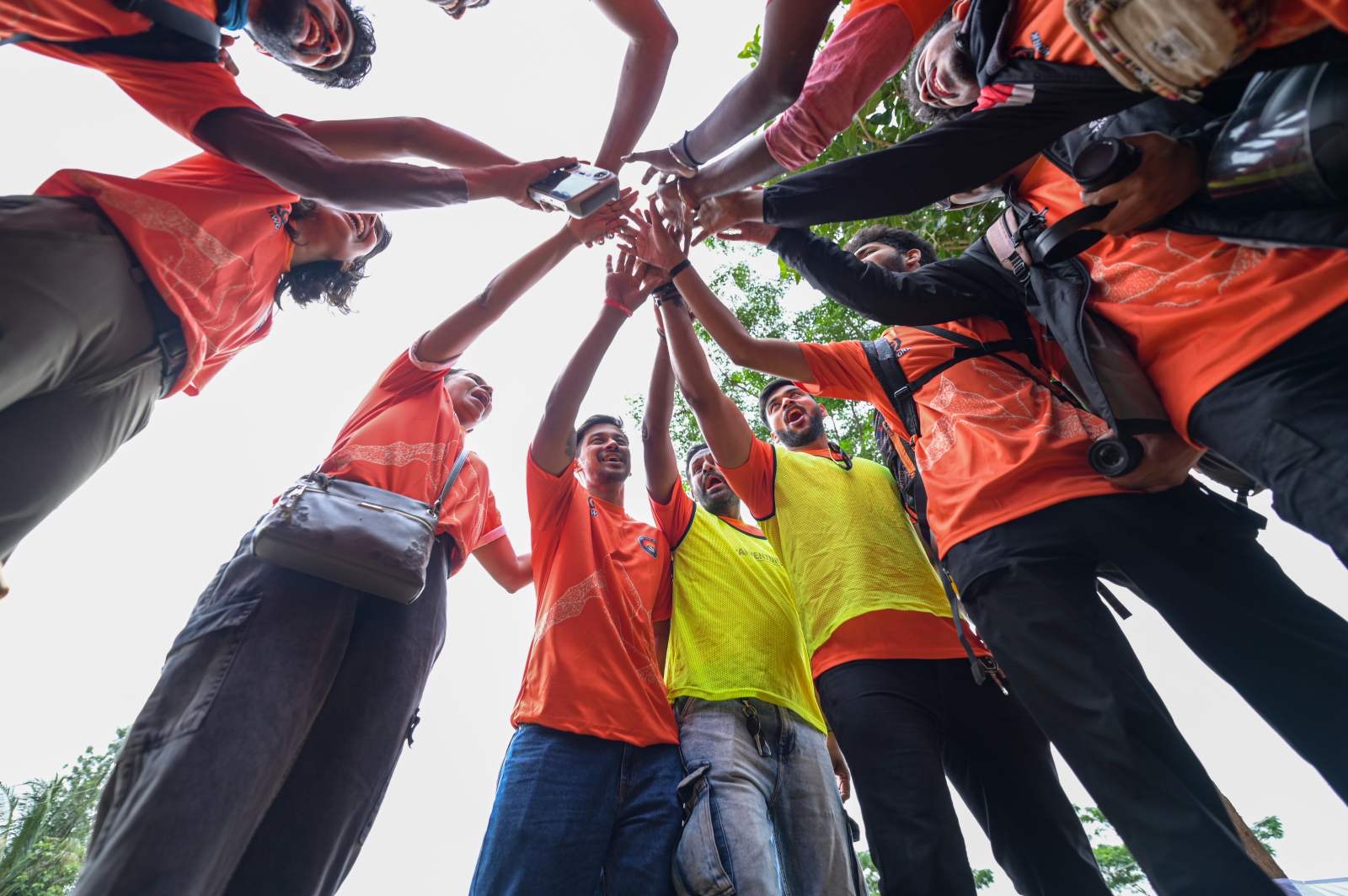 A team with hands joined together in a huddle, seen from below